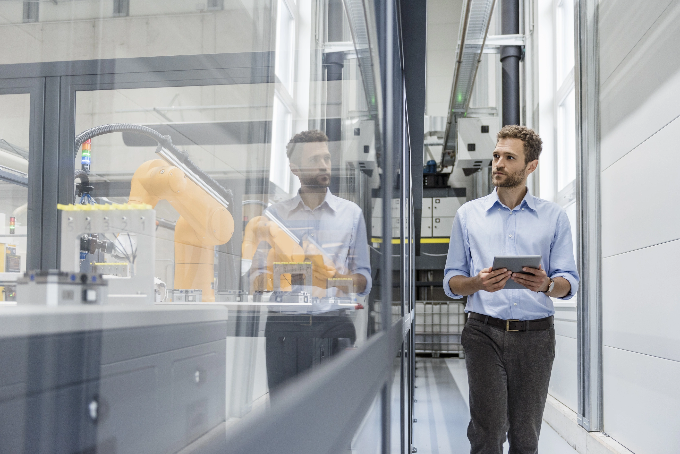 Businessman checking robots with digital tablet in high tech company