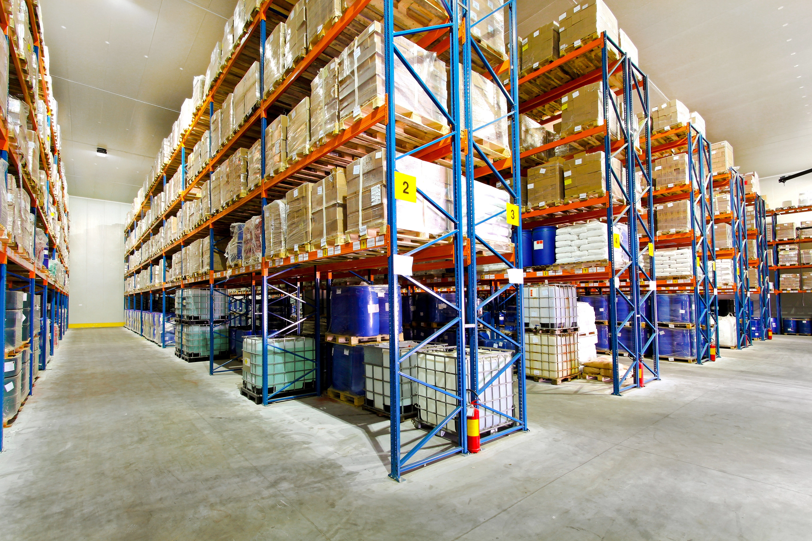 Boxes and barrels in big industrial warehouse.