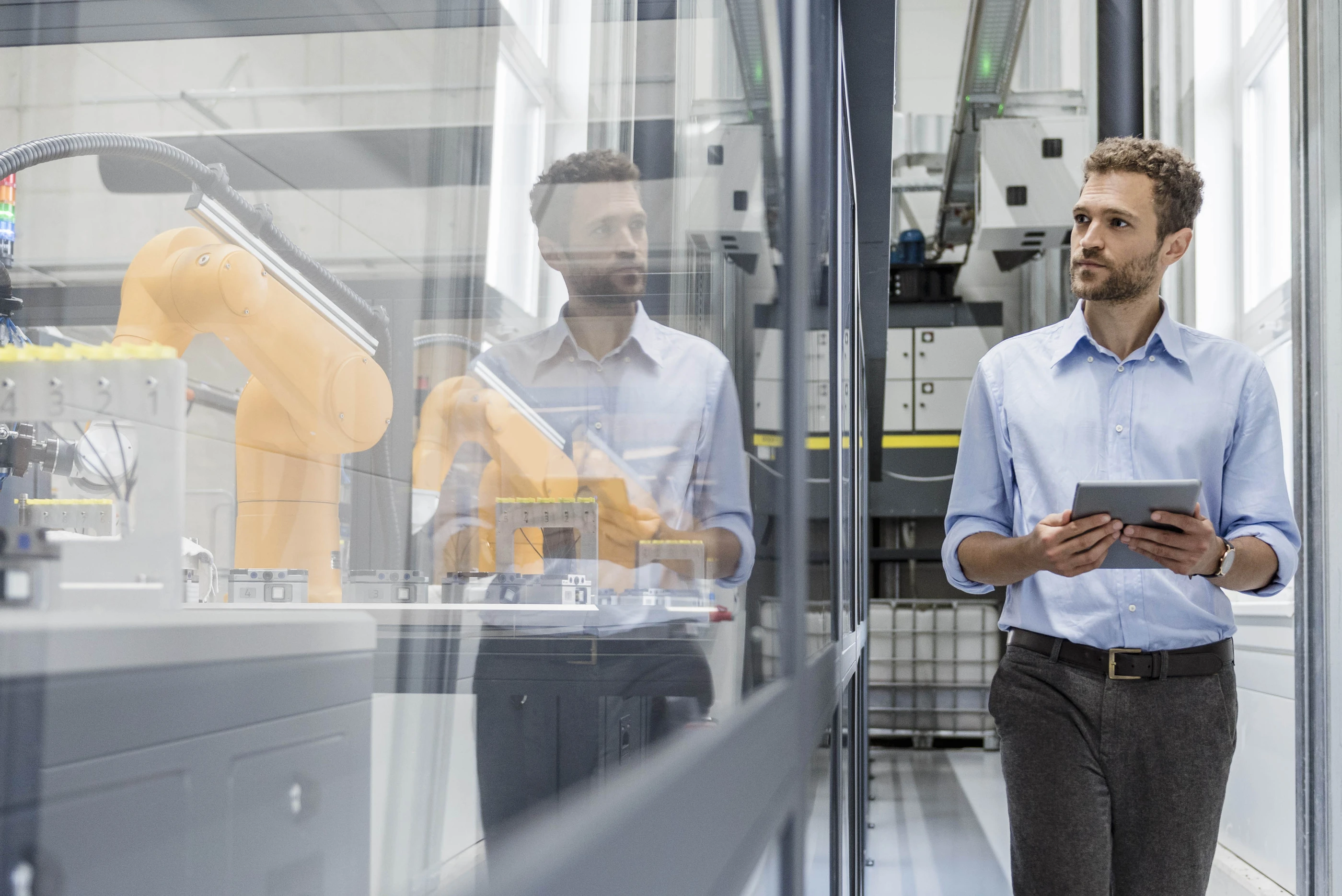 Businessman checking robots with digital tablet in high tech company